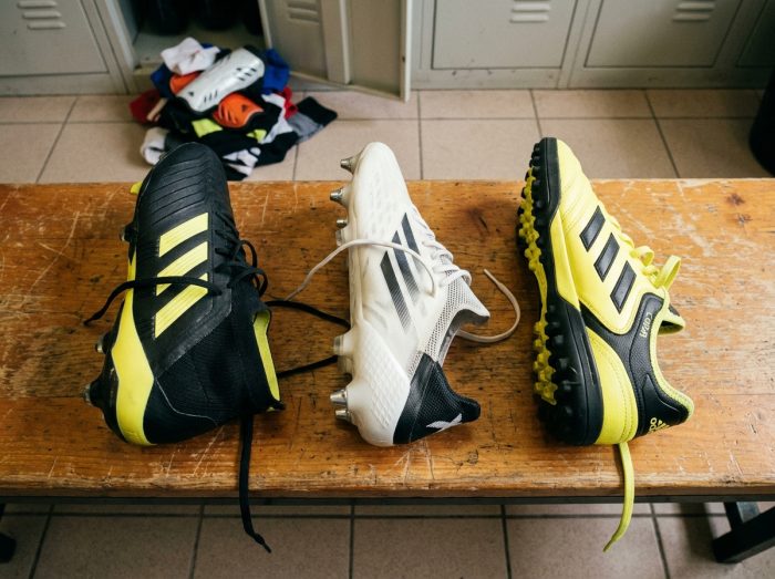 Comparison of three models of adidas boots placed on a bench in a football club locker room
